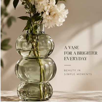 Triple-orb glass vase styled with white blooms and leafy stems on a console